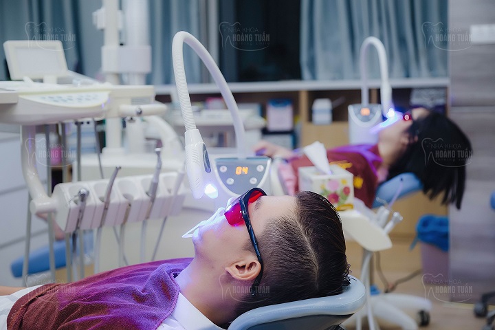 Hình ảnh 2 khách hàng đang được chiếu đèn Laser sau khi bọc răng sứ thẩm mỹ HT Smile